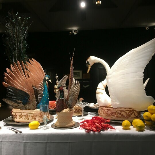 Still life of a table with food and stuffed birds.