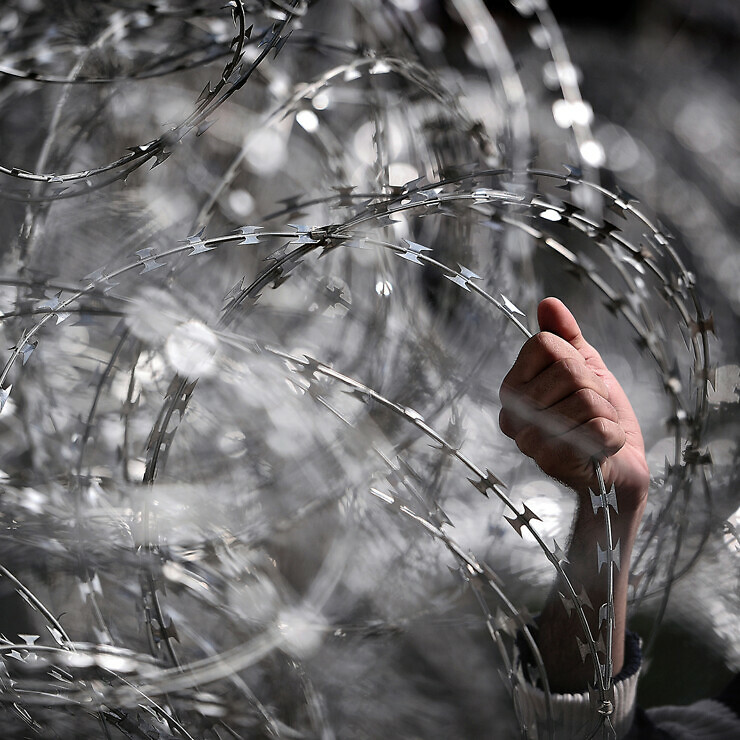 A hand grabs barbed wire.