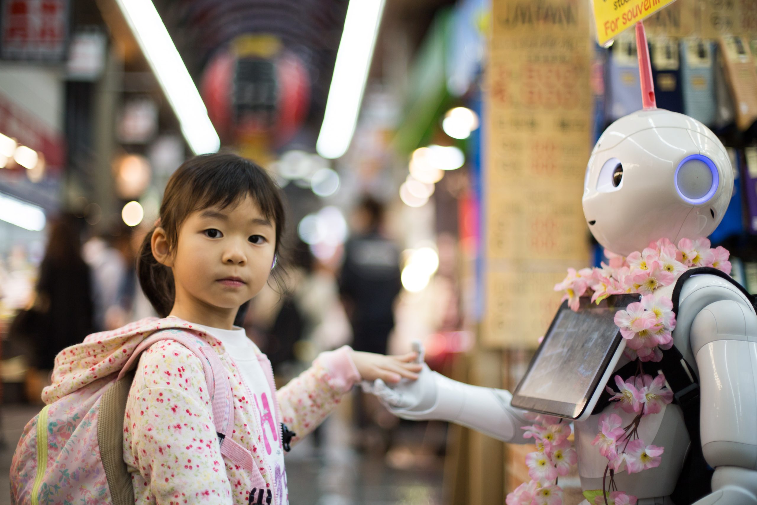 A child holding hands with a robot.