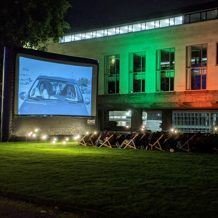 Oudoor film screening at night with a screen and deckchairs.