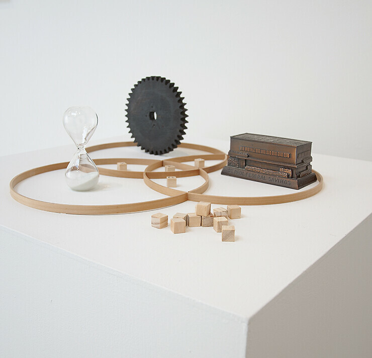 Objects on a plinth are arranged within the intersections of overlapping wooden hoops.