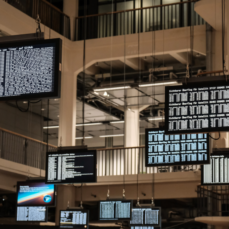 The interior atrium of a modern building is decorated with large TV screens.