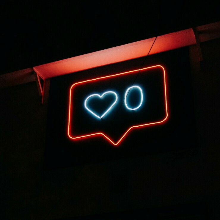 A neon sign in the form of a speech bubble with a social media 'like' heart and the number 0.