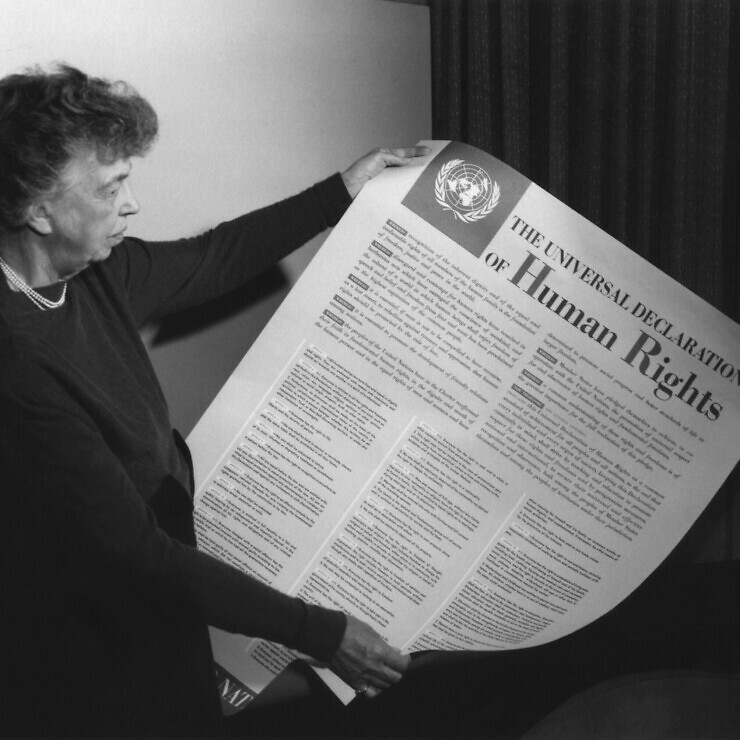 Eleanor Roosevelt looking at a poster entitled 'The Universal Declaration of Human Rights'. The rest of the text is too small to read.