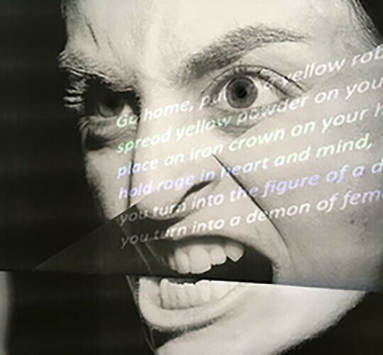 Black and white photograph of an angry face with text projected onto it. The text is not legible in the image.