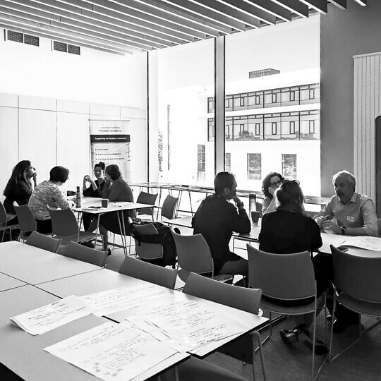 Atmospheric monochrome shot of researchers sitting around tables and talking.