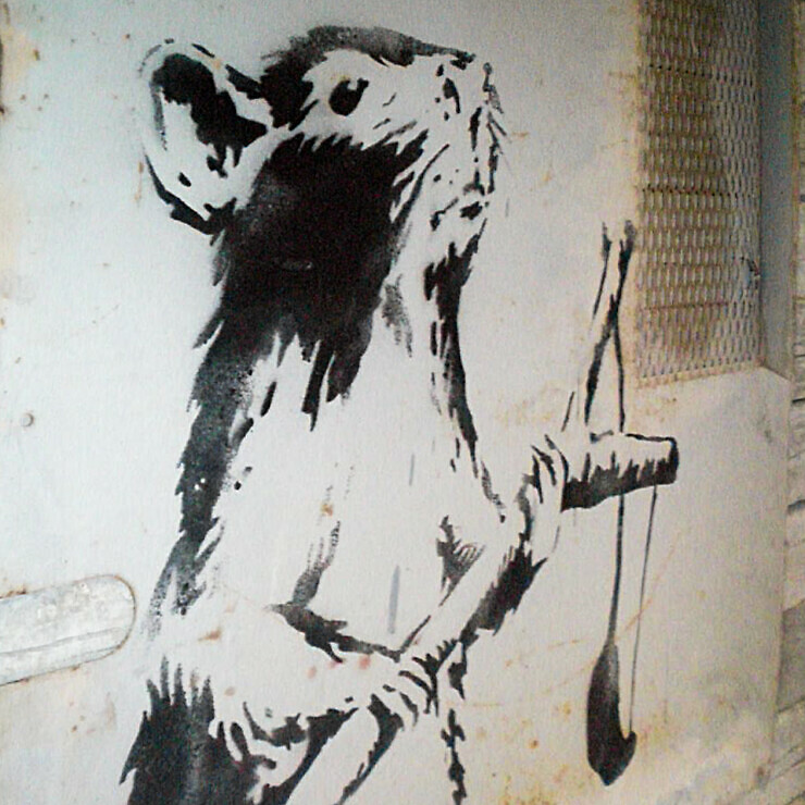 Banksy artwork of a rat holding a sling shot.