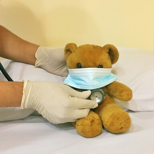 Medic with a stethoscope examines a teddy bear.