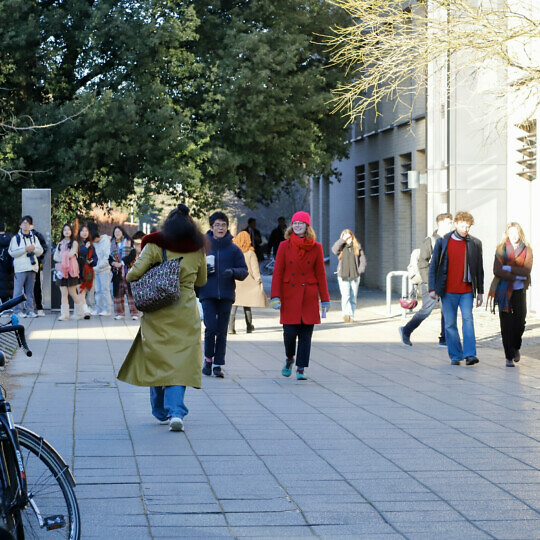 People in bright coats and hats walking past the Alison Richard Building.